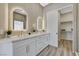 Modern bathroom featuring dual sinks, backlit mirrors, and wood plank walls, leading to a closet at 3218 Squire St, Las Vegas, NV 89135