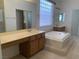 Bathroom with dual sinks, a soaking tub, and a glass block window at 3328 White Bark Pine St, Las Vegas, NV 89129
