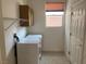Practical laundry room featuring a window, machines, shelving and cabinets at 3328 White Bark Pine St, Las Vegas, NV 89129