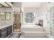 Bright bathroom with tiled tub, fireplace, window, and glass-enclosed shower at 5228 Painted Lakes Way, Las Vegas, NV 89149