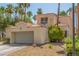 Home featuring a two-car garage, complemented by mature trees at 5228 Painted Lakes Way, Las Vegas, NV 89149