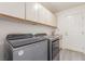 Modern laundry room features gray washer and dryer, white cabinetry, and a utility sink at 5228 Painted Lakes Way, Las Vegas, NV 89149