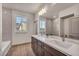 Bright bathroom features double sinks, wood-look tile floor and large mirror at 8528 Baltimore Heights Ct, Las Vegas, NV 89113