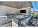 This outdoor kitchen features a built-in grill, sink, TV, and tiled bar, perfect for outdoor entertainment at 8528 Baltimore Heights Ct, Las Vegas, NV 89113