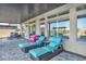 This covered patio features two lounge chairs, a drink cooler, and a dining table, all on a stone patio at 8528 Baltimore Heights Ct, Las Vegas, NV 89113