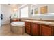 Bright bathroom featuring a large soaking tub, beautiful cabinetry, and lighted vanity mirrors at 8824 Killians Greens Dr, Las Vegas, NV 89131