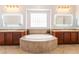 Bright bathroom featuring a large soaking tub, beautiful cabinetry, and lighted vanity mirrors at 8824 Killians Greens Dr, Las Vegas, NV 89131