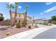 A view of the home's side and front, showcasing the desert landscaping, palm trees and spacious driveway at 8824 Killians Greens Dr, Las Vegas, NV 89131