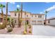 Modern two-story home featuring a stone facade, a two-car garage, and desert landscaping with palm trees at 8824 Killians Greens Dr, Las Vegas, NV 89131