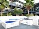 Outdoor lounge area features a fire pit with blue glass and built-in grill with palm trees and the building in the background at 8925 W Flamingo Rd # 319, Las Vegas, NV 89147