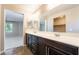Bathroom featuring double sink vanity with dark wood cabinets and a view into an adjacent bedroom at 9050 W Tropicana Ave # 1017, Las Vegas, NV 89147