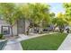 A modern gray home with a healthy green lawn, trees, and a sidewalk leading to the front door at 9050 W Tropicana Ave # 1017, Las Vegas, NV 89147