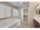 Bright bathroom featuring a relaxing tub, glass enclosed shower, and entry to the walk-in closet at 9074 Iron Cactus Ave, Las Vegas, NV 89148