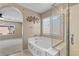 A view of the bright bathroom featuring a garden tub, glass-enclosed shower, and decorative art at 9074 Iron Cactus Ave, Las Vegas, NV 89148