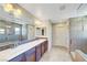 Bathroom with dual sinks, decorative backsplash, walk-in shower, and modern lighting fixtures at 9542 Ridgeglen Ct, Las Vegas, NV 89148