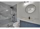 Modern bathroom featuring a tiled shower, blue vanity, and round mirror at 96 Saint Johns Wood Ave, Henderson, NV 89002