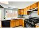 A well-lit kitchen features wood cabinets, granite counters, black appliances, and a large window overlooking the backyard at 1480 Hialeah Dr # B, Las Vegas, NV 89119