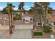 Exterior elevation view of home featuring a 2-car garage, desert landscaping, and mature palm trees at 2344 Valleywood St, Henderson, NV 89014