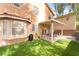 View of the home's backyard with a covered patio, well-kept synthetic grass, and an exterior barbecue at 2354 Buffalo Run Ave, Las Vegas, NV 89123