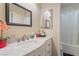 A bathroom with a white vanity, marble countertop, decorative items, and tub with shower at 2354 Buffalo Run Ave, Las Vegas, NV 89123