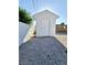 Close-up of a white storage shed with a simple door, nestled beside a white block wall at 3215 Dillon Ave, North Las Vegas, NV 89030