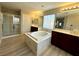 Bathroom featuring a soaking tub, glass shower, dual vanities, and wood-look floors at 3221 Villa Pisani Ct, North Las Vegas, NV 89031