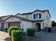 Side view of a tan two story home with a three car garage and low maintenance landscaping at 4076 Topaz Hills Dr, North Las Vegas, NV 89032