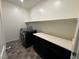 Well-equipped laundry room with front loading black washer and dryer, storage, shelf, and tile flooring at 4076 Topaz Hills Dr, North Las Vegas, NV 89032