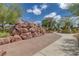 Community walking path with trees and bushes and climbing rocks with a play area in the background at 412 Gracious Way, Henderson, NV 89011