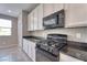 Well-lit kitchen with black appliances, dark countertops, and white cabinets at 4206 Topaz Hills Dr, North Las Vegas, NV 89032