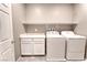 Bright laundry room with modern washer and dryer, storage cabinets, and shelving at 4206 Topaz Hills Dr, North Las Vegas, NV 89032