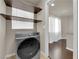 Well-equipped laundry room including a front-load washer and dryer, shelving, and a window at 5234 Tulip Hill Ave, Las Vegas, NV 89141
