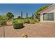 Backyard with desert landscaping with rock covering, green bushes and mature trees at 5401 Broadwater Ln, Las Vegas, NV 89130