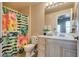 Bright bathroom with a floral shower curtain, a vanity with ample storage, and neutral paint at 5855 Valley Dr # 2106, North Las Vegas, NV 89031