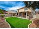 A well-manicured backyard features an artificial turf area and a covered patio with an outdoor kitchen at 775 Wigan Pier Dr, Henderson, NV 89002
