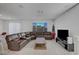 Spacious living room with a large brown sectional sofa, tiled floors, and a view of the outside at 7853 Bethel Heights Ln, Las Vegas, NV 89113