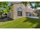 Exterior view of the home and backyard, showcasing an artificial lawn and mature trees at 8416 Kawala Dr, Las Vegas, NV 89128