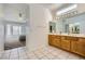 Well-lit bathroom featuring double sink vanity, tile flooring, and access to the main bedroom at 9717 Buckhorn Dr, Las Vegas, NV 89134