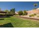 Lush backyard featuring a well-maintained lawn, mature trees and plantings, and a covered patio for outdoor entertaining at 2821 Whispering Wind Dr, Las Vegas, NV 89117