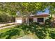 Serene single-story home with mature trees, a red tile roof, and lush green lawn at 2821 Whispering Wind Dr, Las Vegas, NV 89117