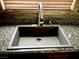 Close up of kitchen sink featuring a gray basin, stylish chrome faucet, granite countertops, and stone backsplash at , Las Vegas, NV 89141