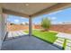 Covered patio leads to backyard with artificial grass, decorative rocks, and a young olive tree at 1000 Cetona Ct, Henderson, NV 89011
