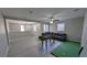 Spacious living room offers light-colored vinyl flooring, a ceiling fan, a foosball table and putting green at 10668 Berkshire Woods Ave, Las Vegas, NV 89166