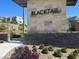 Elegant entrance to Blacktail community showcasing stone details, modern signage, and lush plants at 11658 Midnight Melody Ave, Las Vegas, NV 89138
