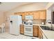 Bright kitchen with white appliances, wood cabinets, tile floors, and an adjacent breakfast nook area at 2085 Joy View Ln, Henderson, NV 89012