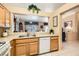 Traditional kitchen featuring wood cabinets, a pass-through window to the living area, and tile flooring at 2085 Joy View Ln, Henderson, NV 89012