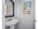 This powder room features a white pedestal sink, a decorative mirror and a bright window view at 3221 Epson St, Las Vegas, NV 89129