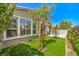 Backyard featuring green turf grass and building exterior with large windows and shutters at 3709 Corte Bella Hills Ave, North Las Vegas, NV 89081