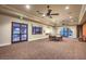 Large carpeted common room with ceiling fans, tables, and chairs with exterior view through doors and windows at 3709 Corte Bella Hills Ave, North Las Vegas, NV 89081