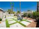 Lush backyard with artificial turf, seating area, and beautiful palm trees, perfect for relaxation and entertaining at 6100 Cocktail Dr, Las Vegas, NV 89130